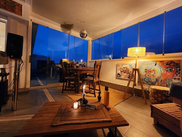 A cozy room with a wooden table, chairs, a small rug, and a painting on the wall. - The Penthouse Tarifa - Artist's Residence Oasis (Tarifa)