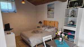 A bedroom with a bed, bedside table, lamp, and a small table with a vase of flowers. - A SWEET REST (Chauvé)