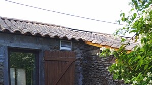 A stone building with a tiled roof, a wooden door, and a small patio with a table and chairs. - A SWEET REST (Chauvé)