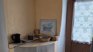 A small kitchen with a coffee maker, a framed picture, and a vase with dried plants. - A SWEET REST (Chauvé)