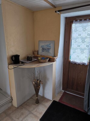 A small kitchen with a coffee maker, a framed picture, and a vase with dried plants. - A SWEET REST (Chauvé)