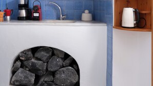 Una cucina con camino in pietra, un lavello e diversi elettrodomestici.
