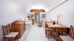 Zona pranzo con tavolo in legno, sedie e divano. Si nota un armadio con ante in vetro e un tavolino con un vaso.