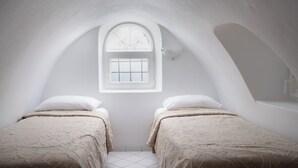 Una camera da letto mansardata con due letti, una finestra a lucernario e un pavimento piastrellato di bianco.