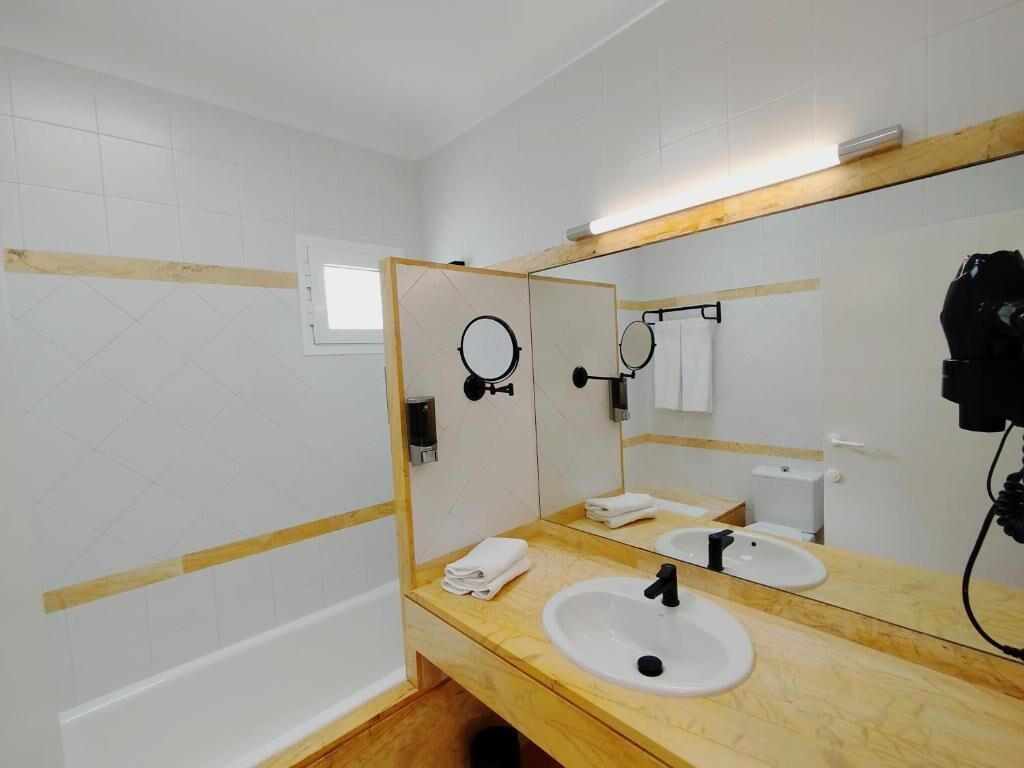 Une salle de bain avec un meuble-lavabo en bois, un lavabo blanc, un miroir et un porte-serviettes.