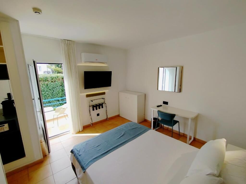 Habitación de hotel con cama, escritorio, televisión y vistas al exterior.