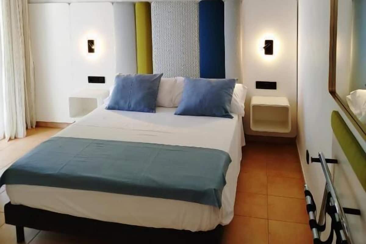 Una habitación de hotel con cama, mesitas de noche, un espejo y un soporte para bicicletas.