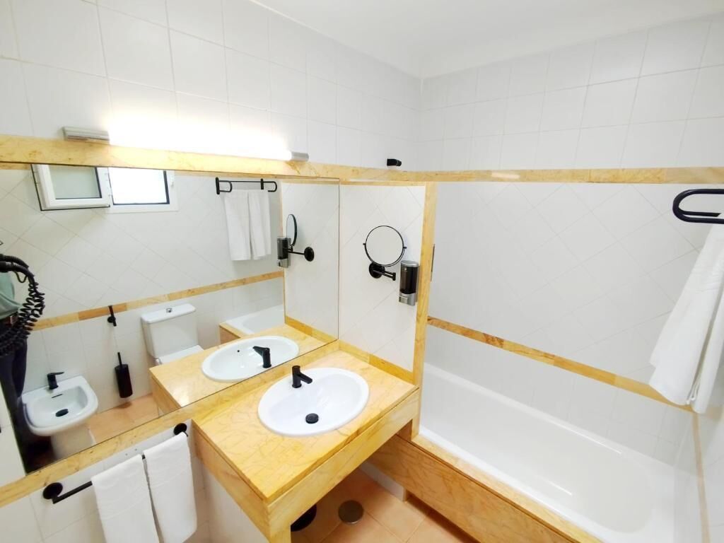 A bathroom with two sinks, a bathtub, and a mirror.