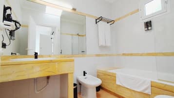 Een badkamer met een marmeren wastafel, een bidet, een bad en een grote spiegel.