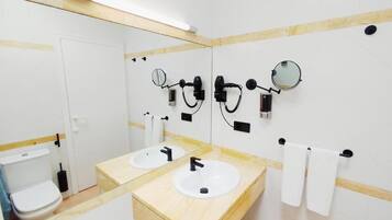 Un baño con dos lavamanos, un inodoro y un espejo.