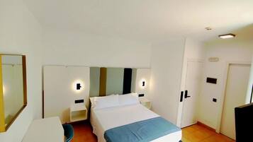 Una habitación de hotel con cama, mesitas de noche, escritorio y silla.
