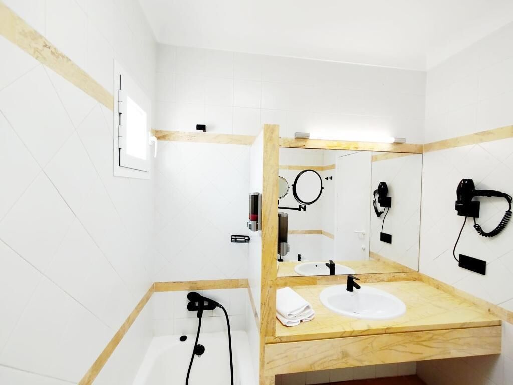 Een moderne badkamer met een houten wastafel, een grote spiegel, een bad en een handdoekrek.