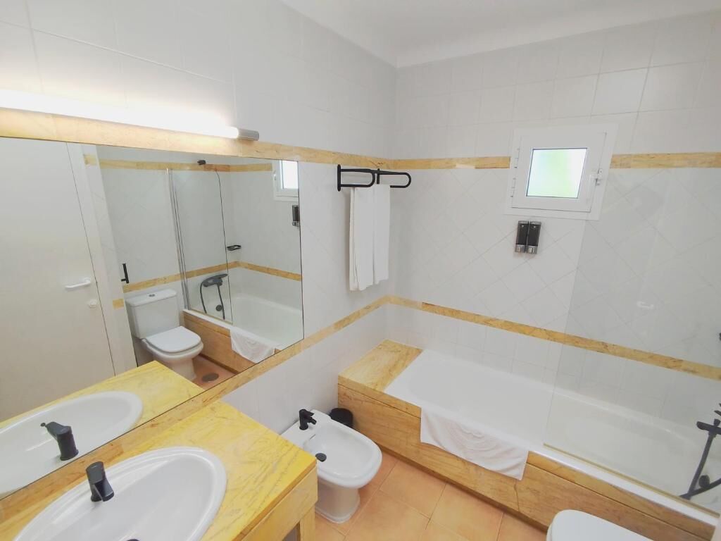 Un baño con dos lavamanos, un inodoro, una bañera y una ducha.