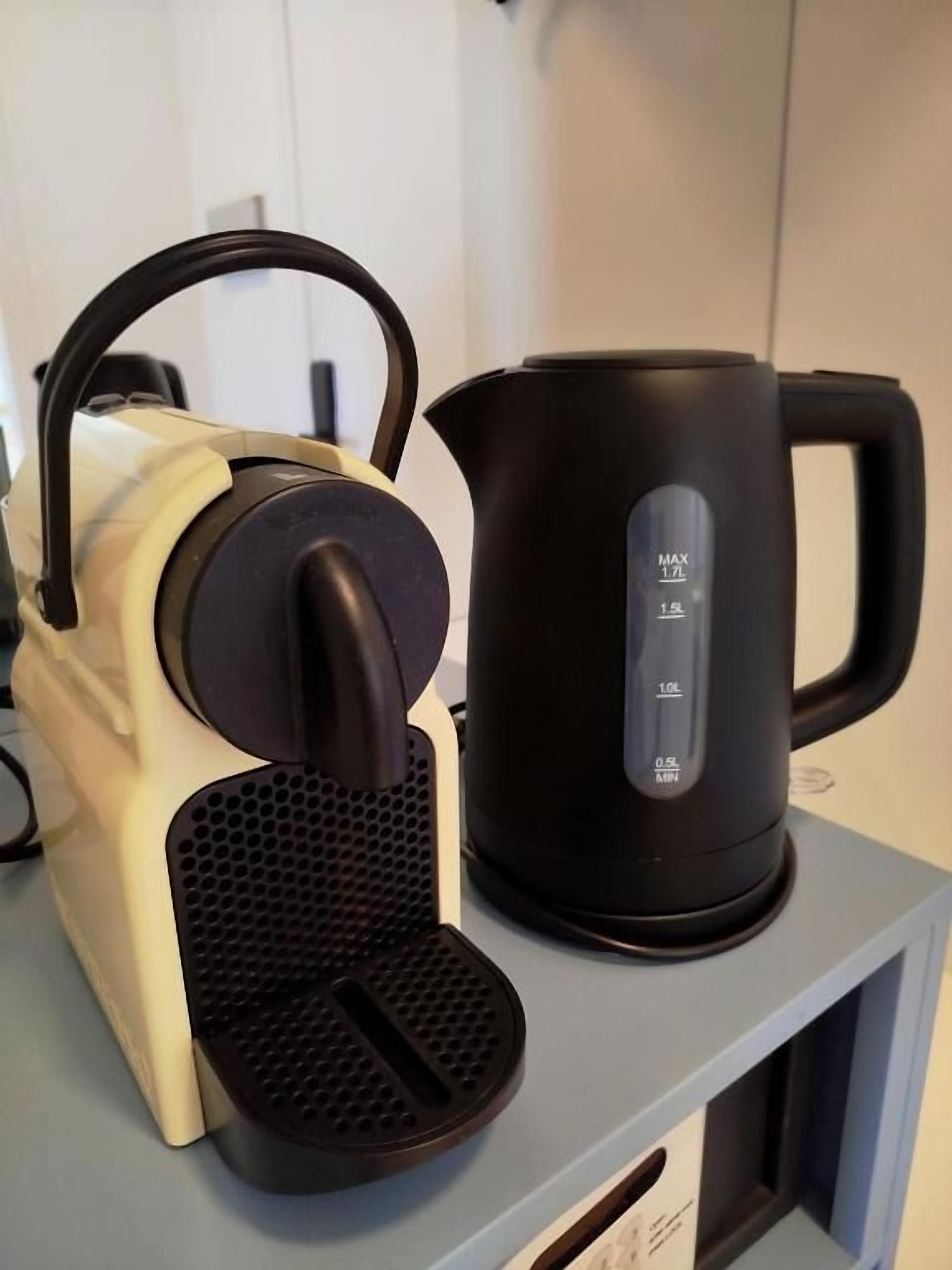 A kitchen with a coffee maker and a black electric kettle on a countertop.