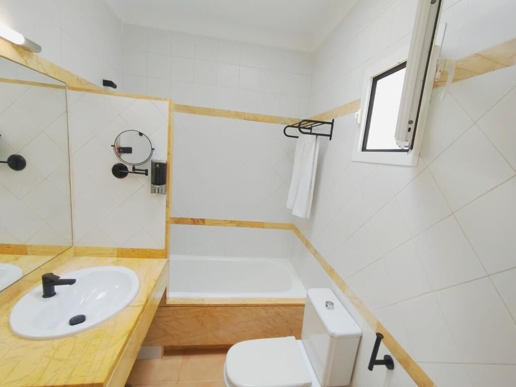 Un baño con lavamanos, inodoro y bañera.