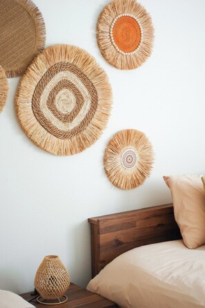 A bedroom with a wooden headboard, a bed with a beige pillow, and a wall adorned with woven wall art.