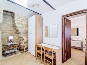 Ein Zimmer mit einer Steinwand, einem Holzschrank, einem weißen Waschbecken und einem Spiegel.