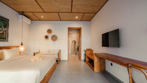 A bedroom with a bed, bedside table, and a TV mounted on the wall. - Casa Nova (Pecatu)