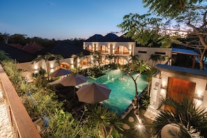 A modern resort with a swimming pool, outdoor umbrellas, and lush greenery. - Casa Nova (Pecatu)