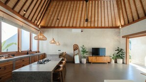 A modern kitchen with a central island, wooden cabinets, and a large window. - Casa Nova (Pecatu)