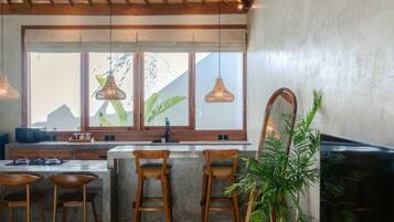 Una cocina moderna con un ventanal grande, techo de madera y taburetes de bar.