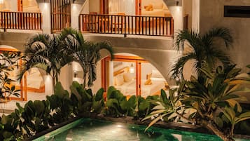 Un hotel con piscina, varios balcones y abundante vegetación.