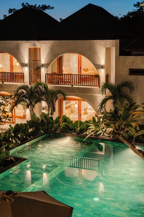 Un hotel con piscina, varios balcones y abundante vegetación.