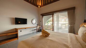 Habitación de hotel con cama, televisión, escritorio, silla y balcón con vistas.