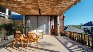An outdoor patio with wicker furniture, a ceiling fan, and a view of the surrounding area. - Casa Nova (Pecatu)