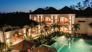 A resort with a swimming pool, outdoor seating, and a large building with multiple balconies. - Casa Nova (Pecatu)