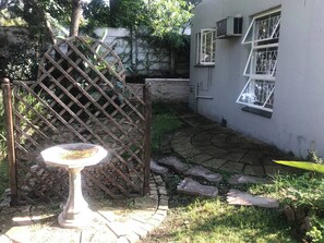 Een tuin met een kiezelpad, een metalen poort en een vogelbad.