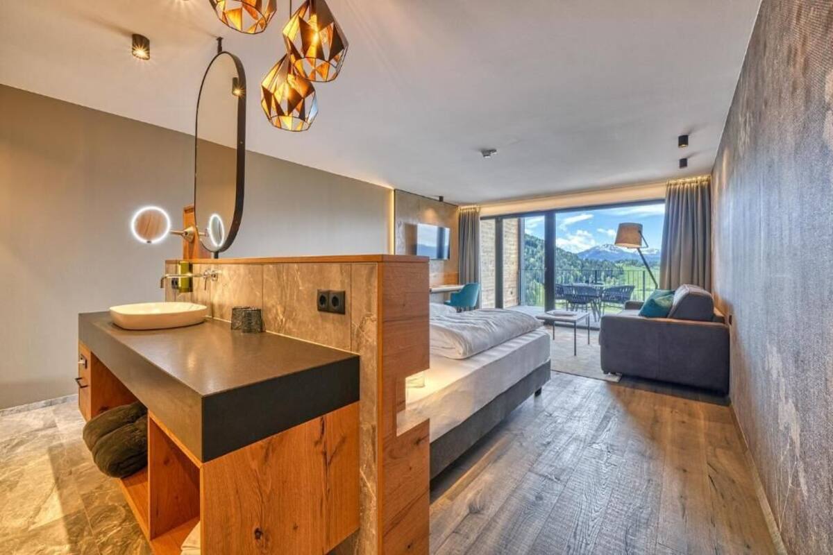 Une chambre moderne avec une coiffeuse en bois, un grand lit et une vue sur l’extérieur.