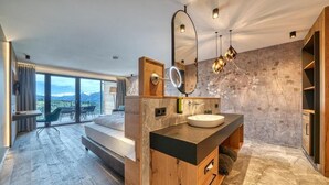 Une salle de bain moderne avec un grand miroir, un meuble-lavabo en bois et une vue sur les montagnes.