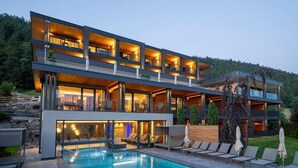 Un hôtel moderne à plusieurs étages, doté d’une piscine, d’un espace extérieur aménagé et offrant une vue sur le paysage environnant.