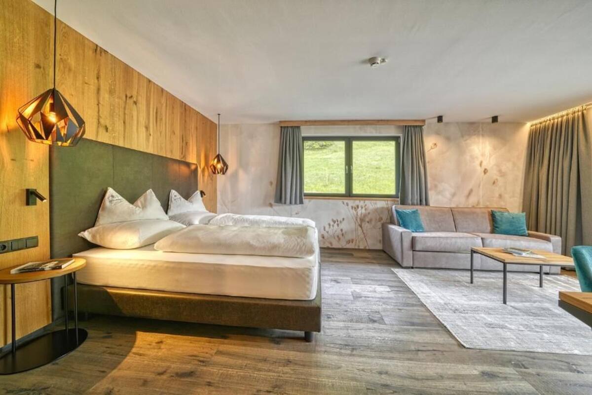 Une chambre moderne avec un lit, un canapé, une table basse et une fenêtre avec des rideaux.