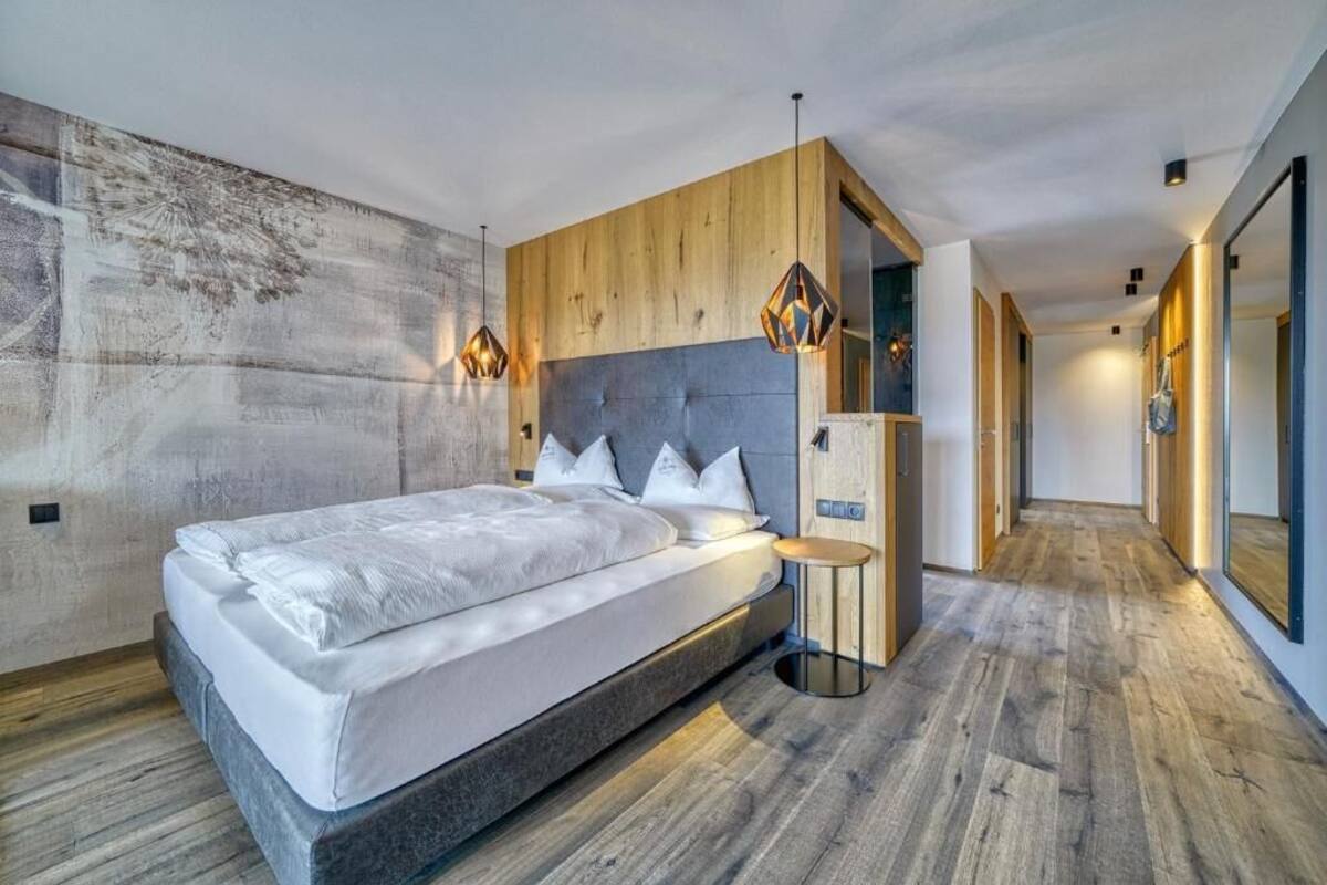 Une chambre à coucher moderne avec un grand lit, un mur revêtu de panneaux en bois et des luminaires suspendus.