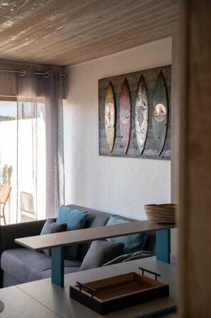 Une pièce comprenant un canapé, une table en bois et une œuvre d’art représentant une planche de surf, accrochée au mur.
