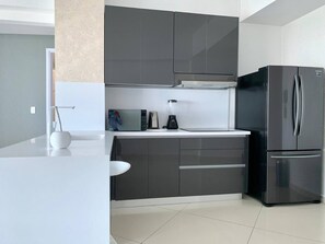 Eine moderne Küche mit einem eingebauten Kühlschrank, einer Mikrowelle und einem Mixer auf der Arbeitsfläche.