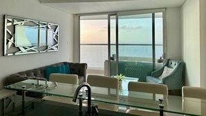 Een moderne kamer met een glazen tafel, leren bank en uitzicht op zee.