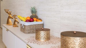 A white cabinet with decorative golden reindeer and a wicker basket containing fruits.