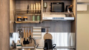 A compact kitchen with wooden cabinets, a microwave, a coffee machine, and a mini-fridge.