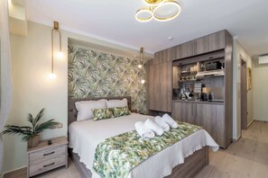 A bedroom with a bed, bedside table, and a built-in kitchen area.