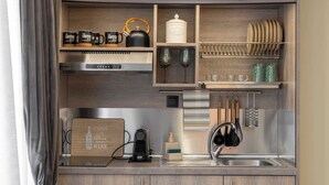 Eine kleine Küche mit Holzschränken, einem eingebauten Backofen, einer Kaffeemaschine und einem Weinkühlschrank.