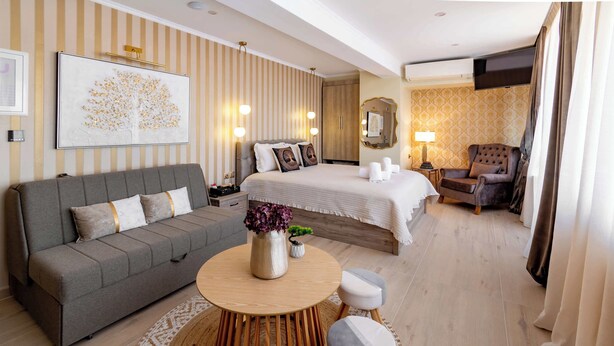 Ein Hotelzimmer mit einem Bett, einem Sofa, einem runden Holztisch, einem Spiegel und einem Sessel.