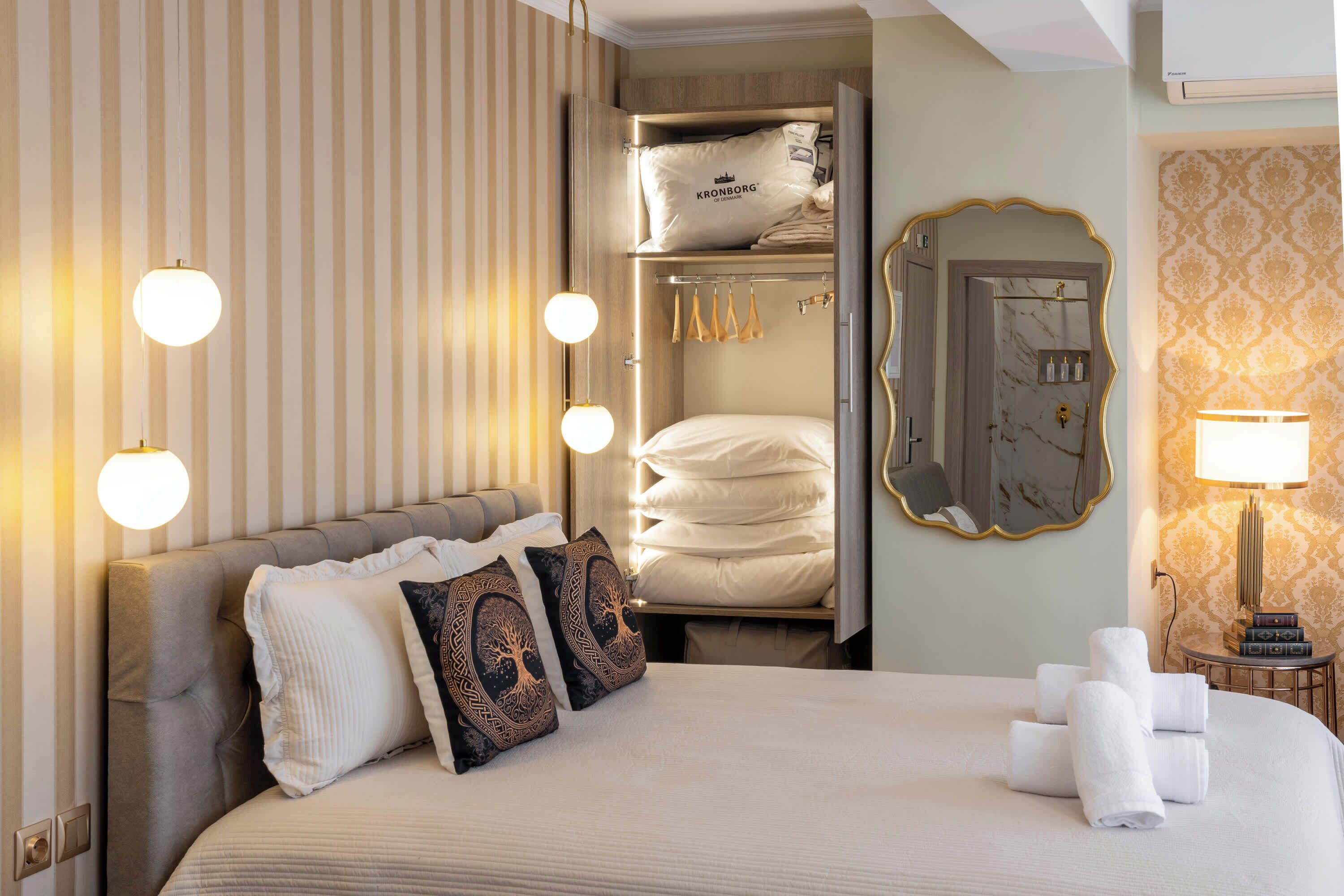 Una camera d'albergo con un letto, un armadio, uno specchio e un comodino con una lampada.