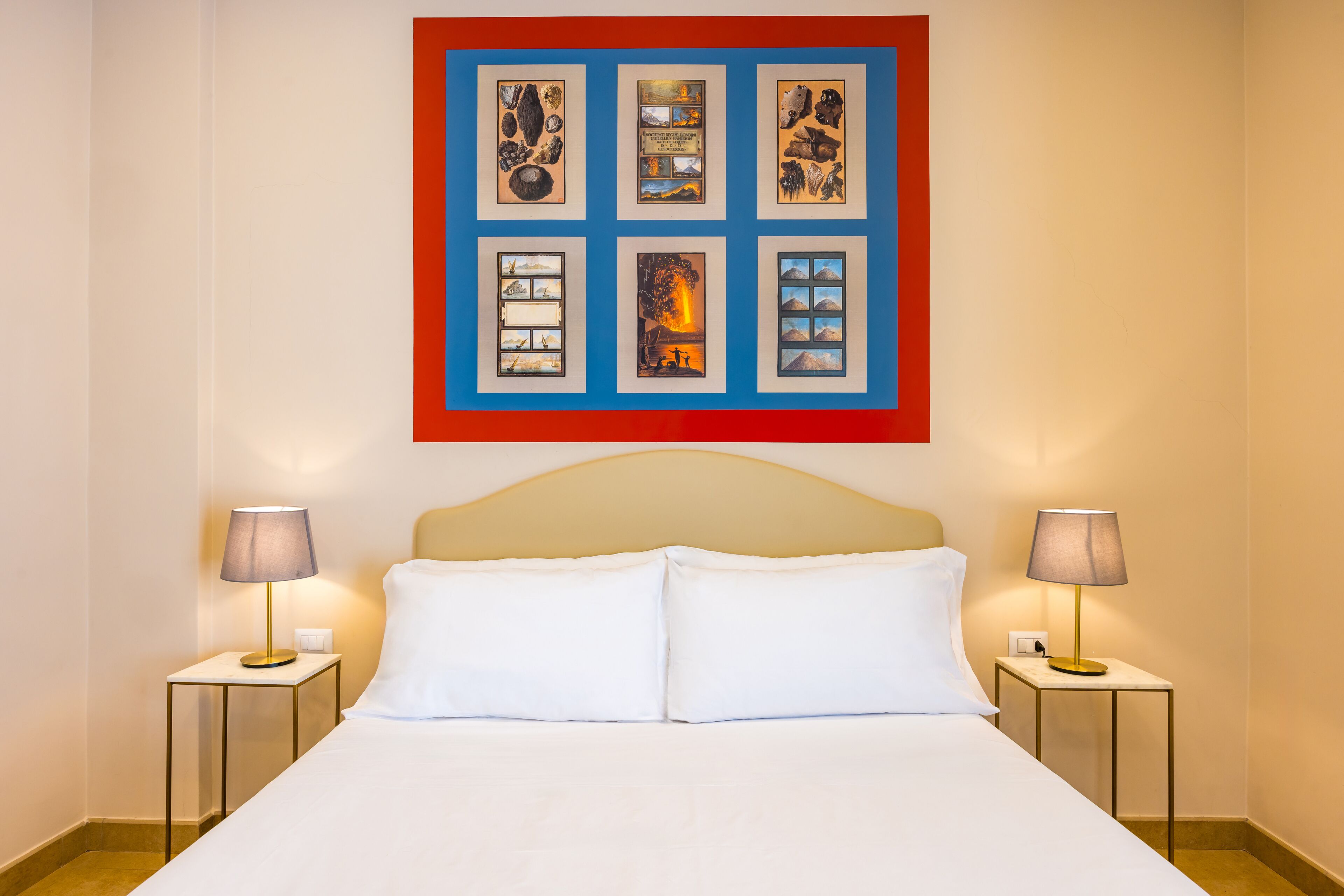 Une chambre d’hôtel avec un grand lit, deux tables de chevet et une œuvre d’art encadrée au-dessus du lit.