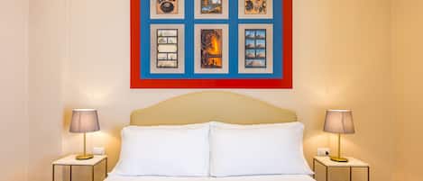 Una habitación de hotel con una cama grande, dos mesitas de noche y una obra de arte enmarcada sobre la cama.