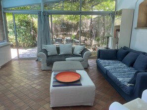 Ein Wohnzimmer mit einer Couch, einem Hocker und einem Esstisch mit einem Teller.