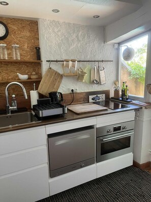 A modern kitchen with a stainless steel sink, a Bosch oven, and a wooden backsplash. - A charming 65 m² house with a very large pool (Aix-en-Provence)