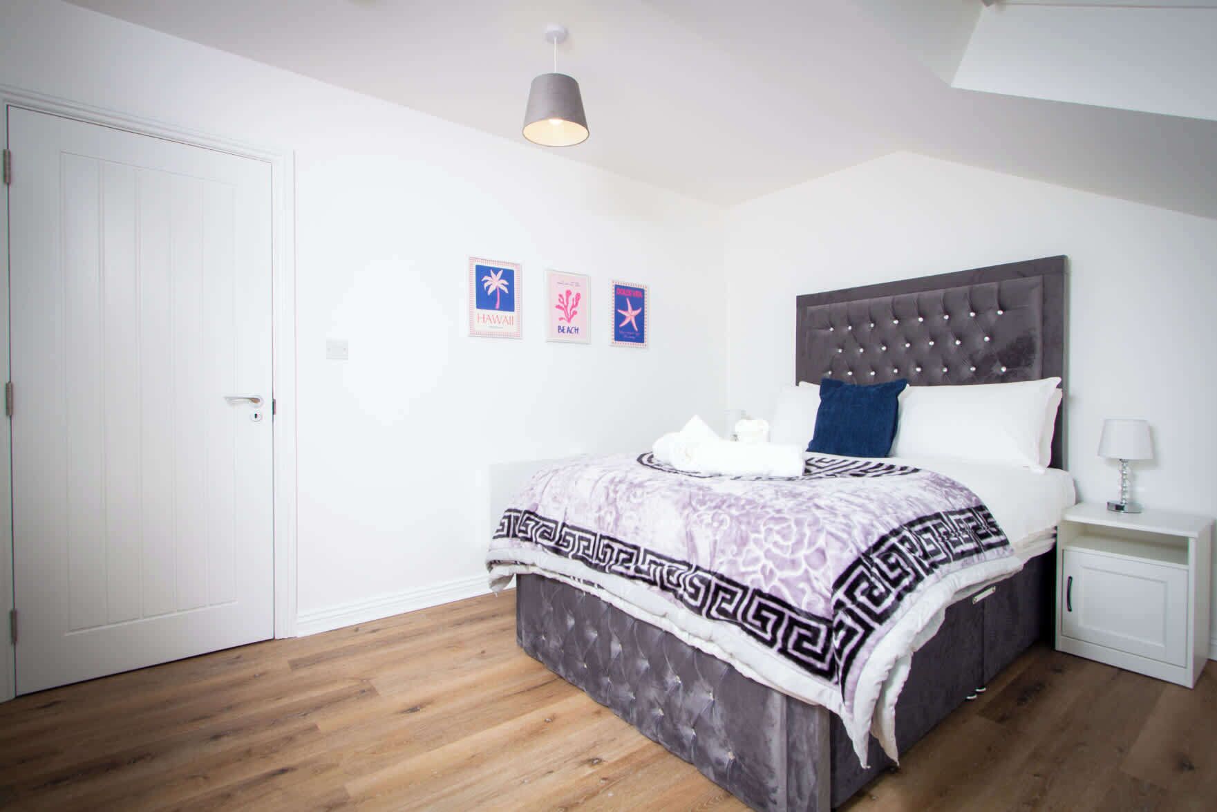 A bedroom with a bed, a nightstand, a lamp, and a ceiling light.
